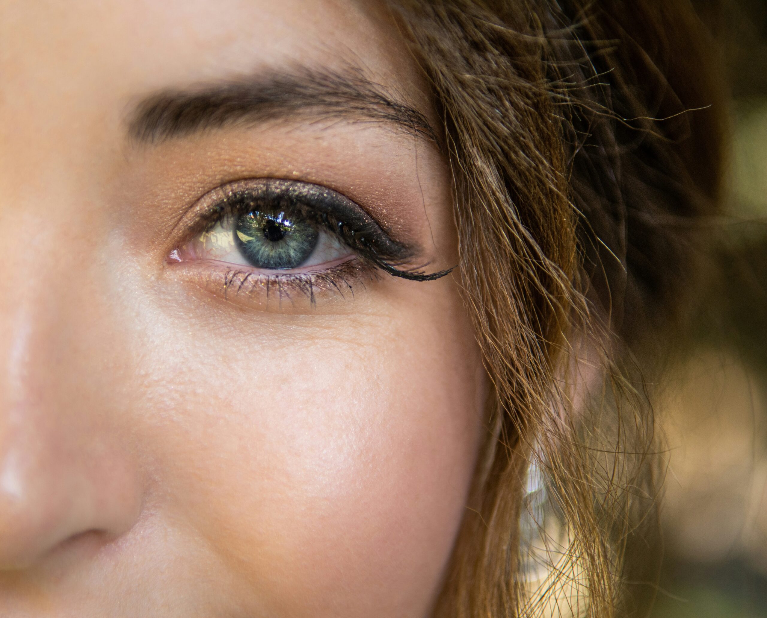 Close-up shot of someone's flawless makeup look featuring soft pink and gold tones.