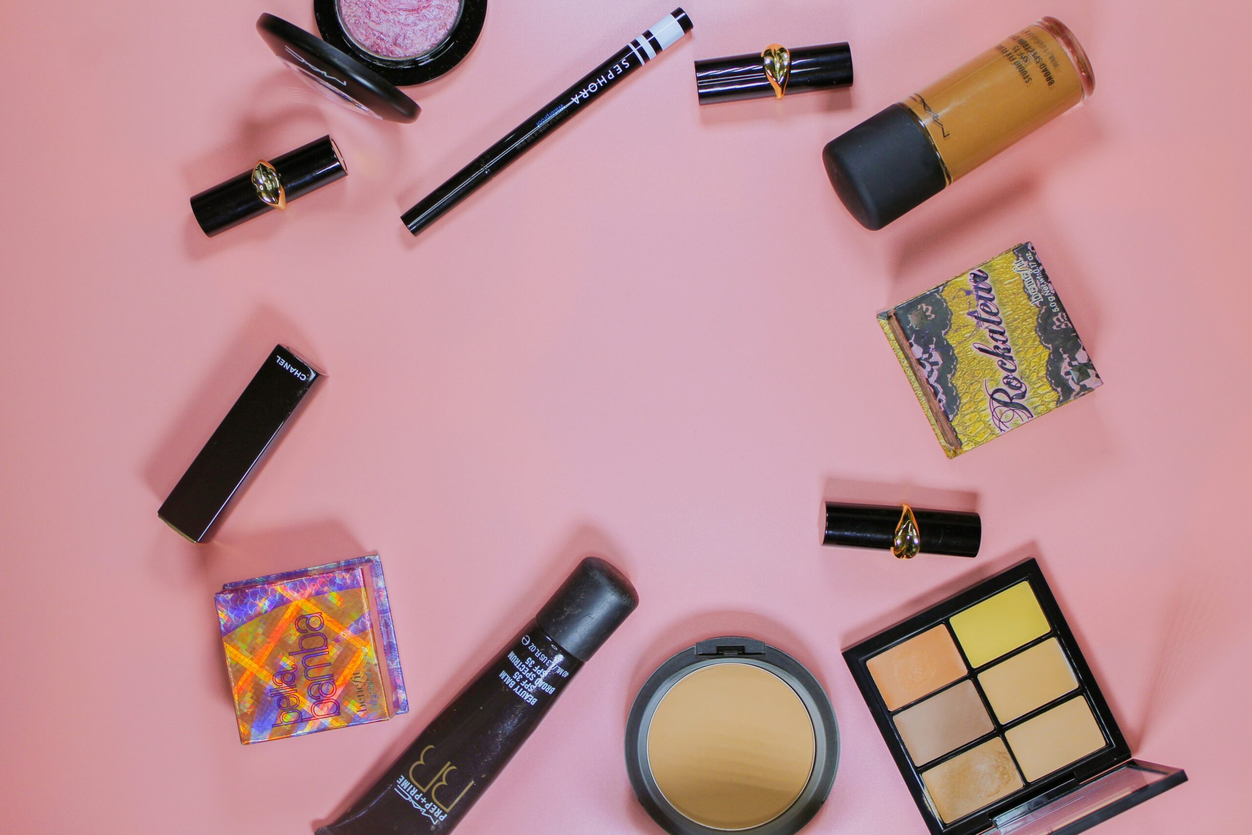 Fenty Beauty Snap Shadows displayed on a table next to other travel-sized makeup essentials.