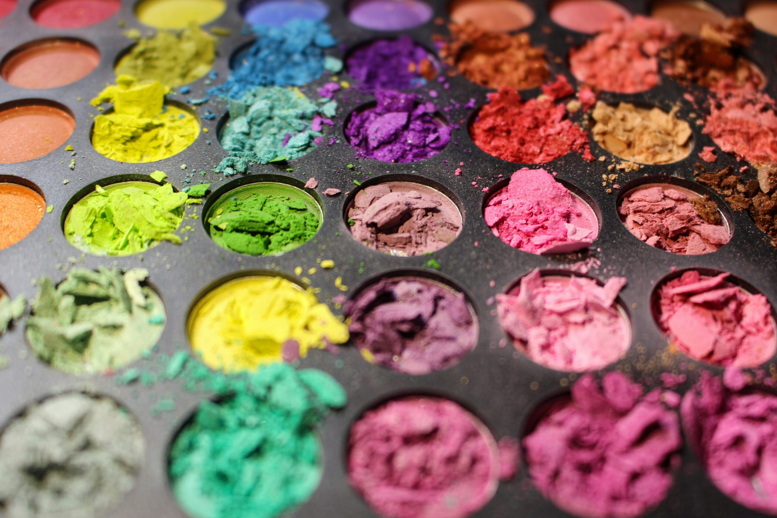 A model wearing a vibrant eyeshadow look featuring teal and gold shades.