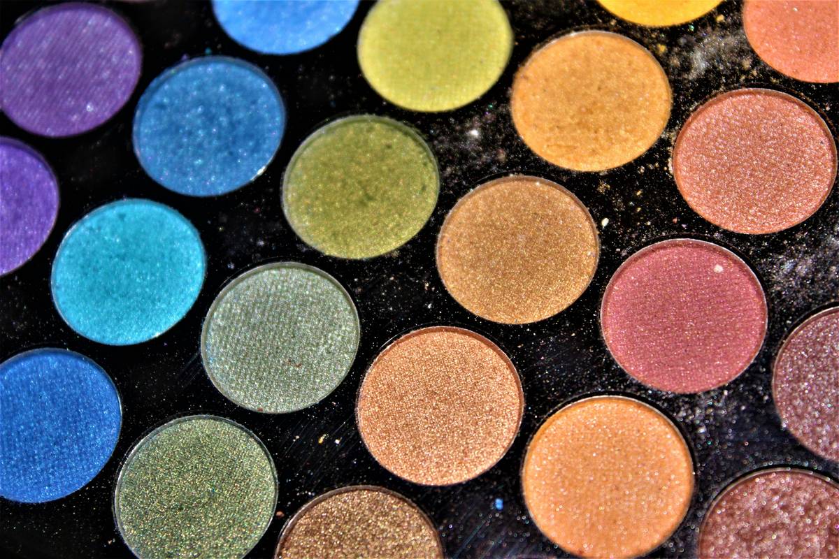 A close-up of a brightening complexion palette featuring gold highlights, soft pink blush, and warm bronzer tones
