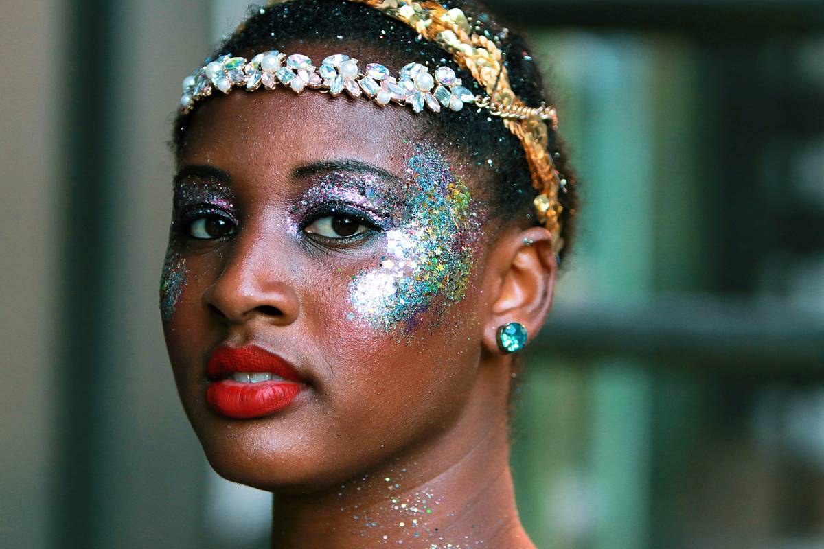 A makeup artist applying eyeshadow with brushes to a model's eyelid.