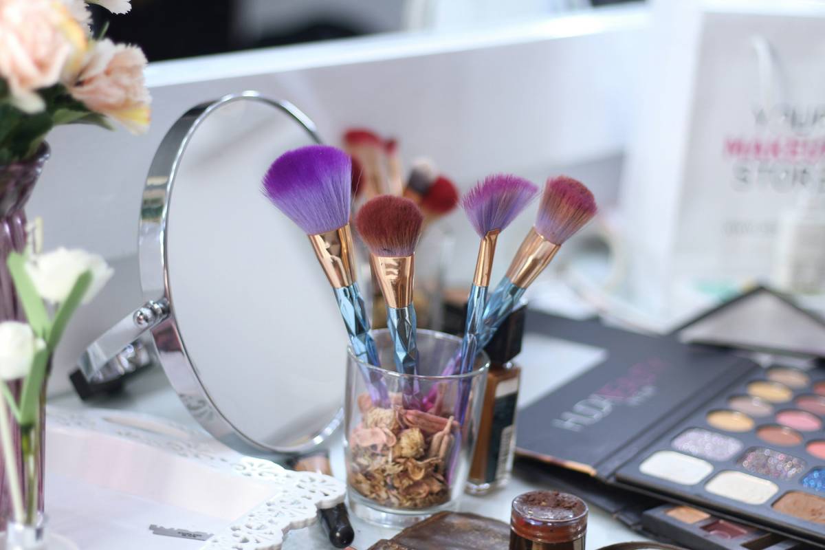 A flat-top blending brush being used to apply eyeshadow from a multi-functional palette.